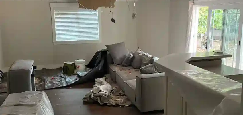 Storm damage left a large section of the living room ceiling collapsed before restoration began.